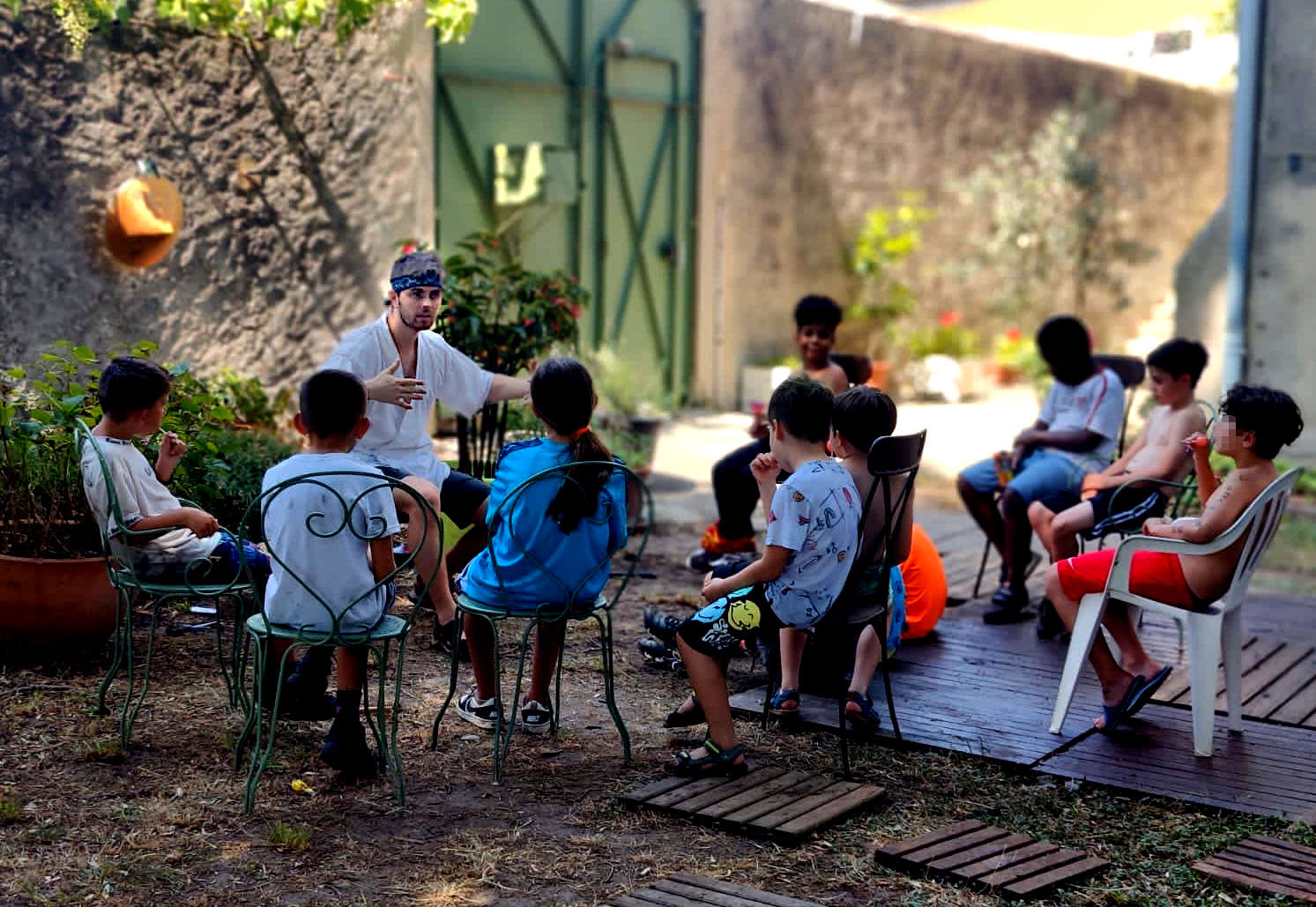 Un homme habillé de blanc, raconte assis devant un groupe d'enfants.